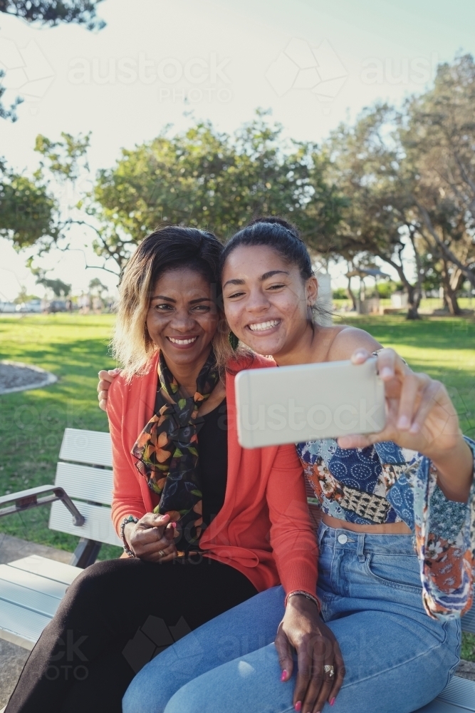 African mother and multicultural teen daughter taking selfie - Australian Stock Image