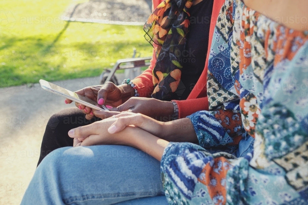 African mother and multicultural teen daughter using mobile phone - Australian Stock Image