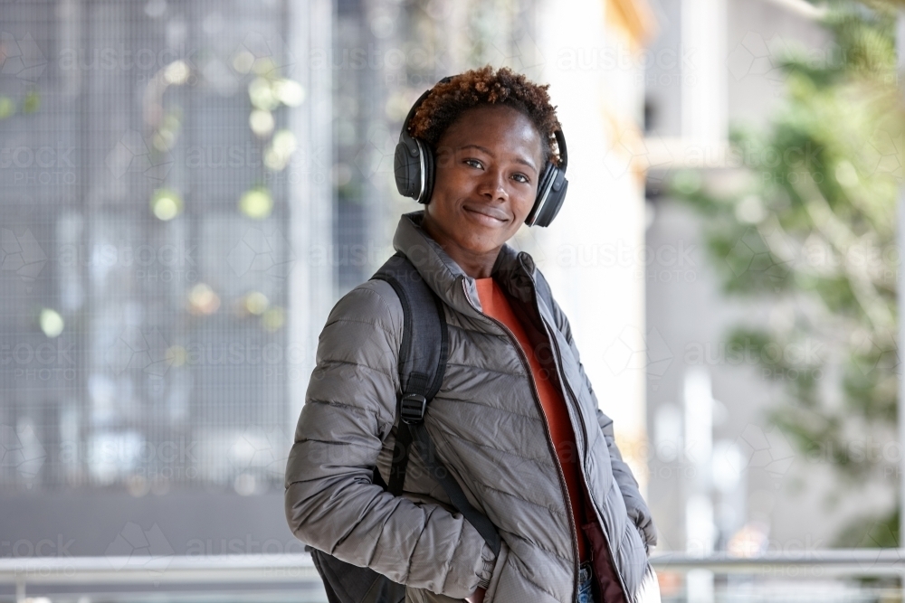 African woman listening to music in city with wireless headphones - Australian Stock Image