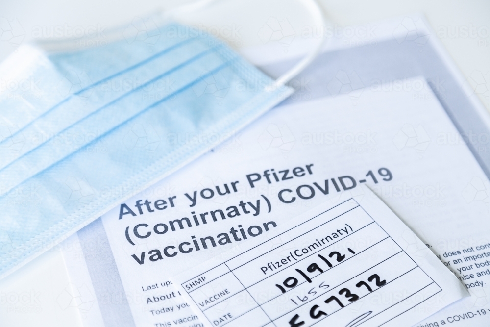 After your Pfizer (Comirnaty) COVID-19 Vaccination information sheet and medical mask - Australian Stock Image