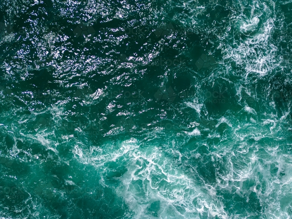 An aerial shot of a turquoise blue waters with white foam patterns on the surface - Australian Stock Image