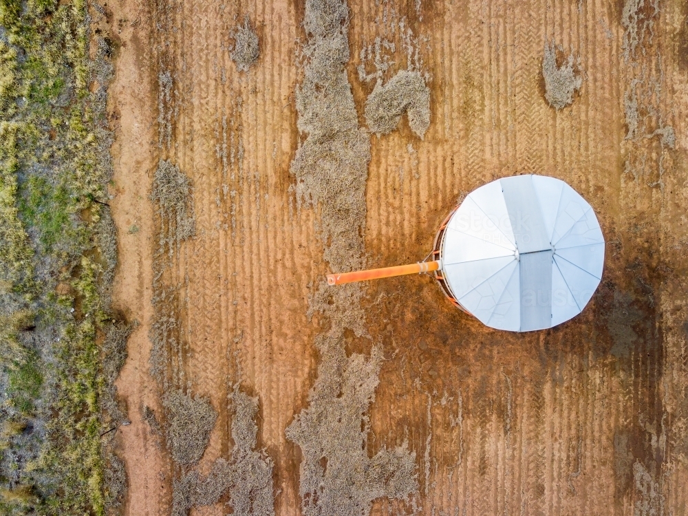 An aerial view of a grain bin in a bare paddock - Australian Stock Image