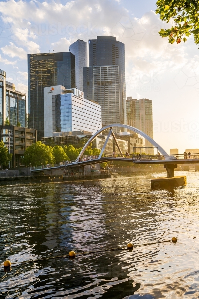 An arched bridge over an inner city river with high rise buildings along its banks - Australian Stock Image
