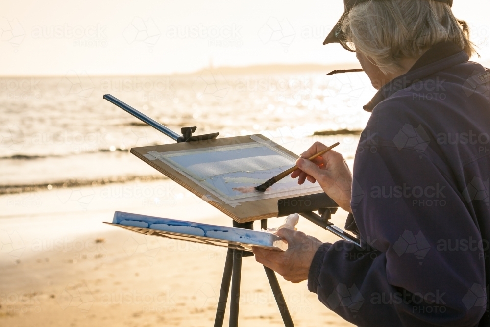 An artist painting on an easel on a beach - Australian Stock Image