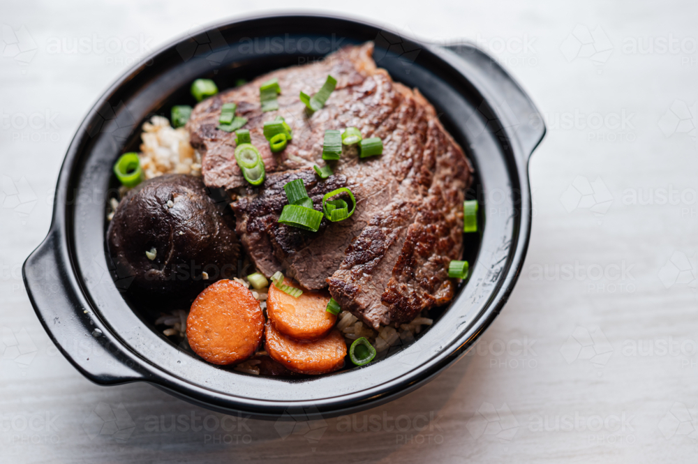 An Asian beef rice dish features tender slices of meat layered over rice - Australian Stock Image