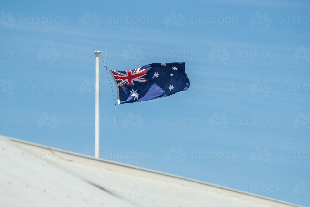 An Australian flag flying over a tin roof - Australian Stock Image