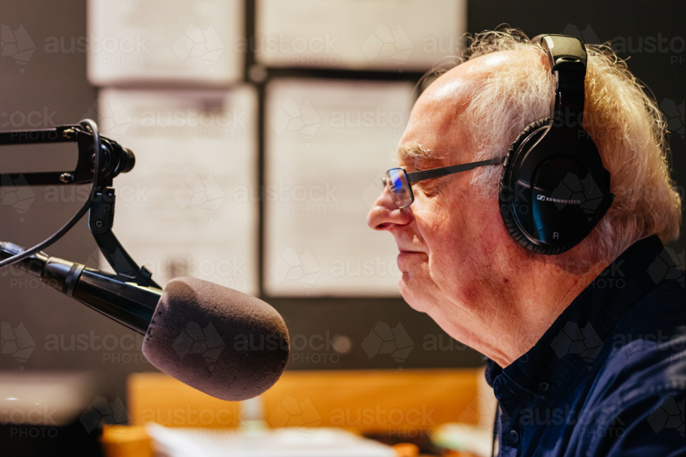 An elderly caucasian man DJs and presents his music show on live radio in Castlemaine, Australia - Australian Stock Image