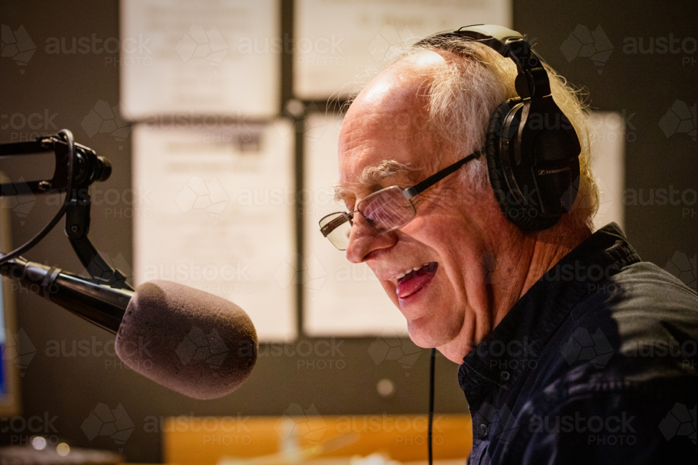 An elderly caucasian man DJs and presents his music show on live radio in Castlemaine, Australia - Australian Stock Image