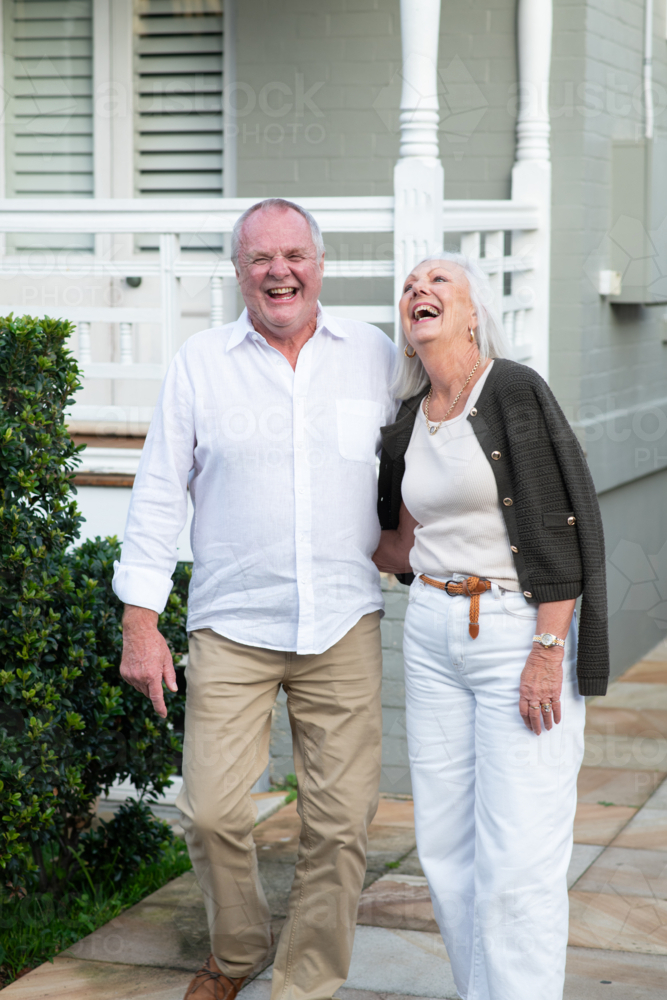 An elderly couple  outside their home, laughing - Australian Stock Image