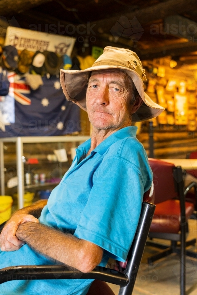 An elderly man sitting in a chair in an outback pub - Australian Stock Image