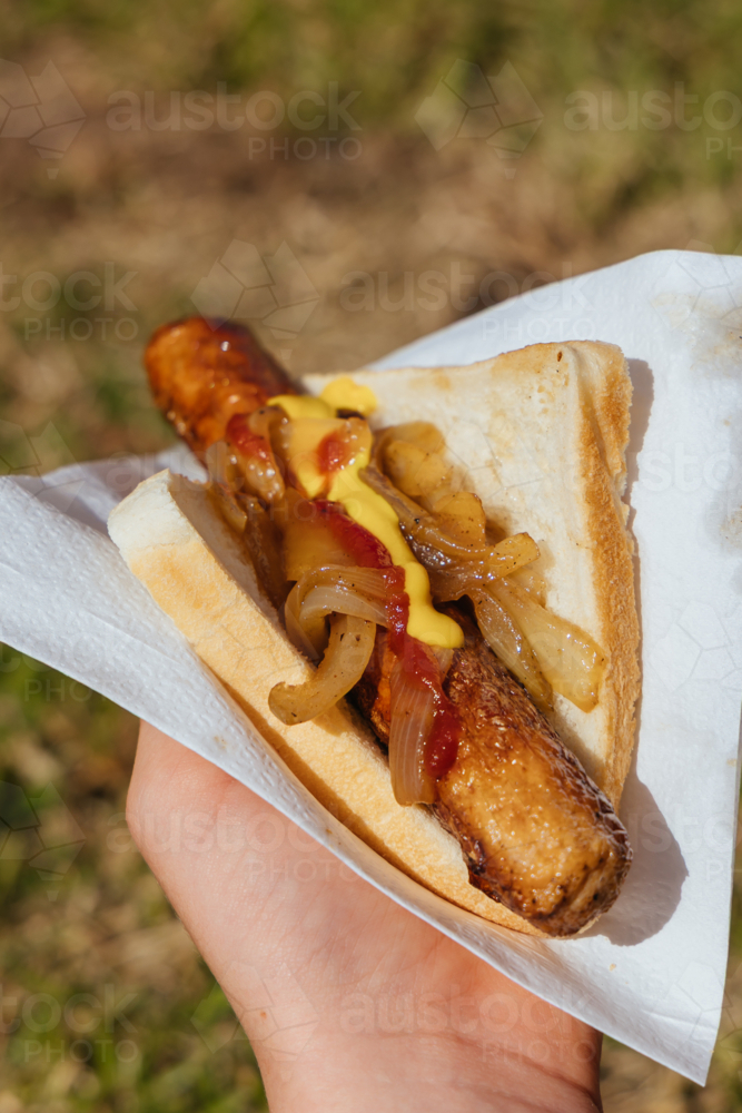 An election day sausage in bread from a BBQ, colloquially known as a sausage sizzle - Australian Stock Image