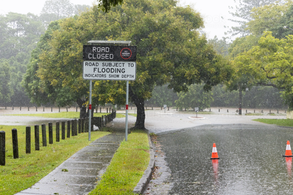 An electronic street sign saying road closed due to flooding with water in background - Australian Stock Image
