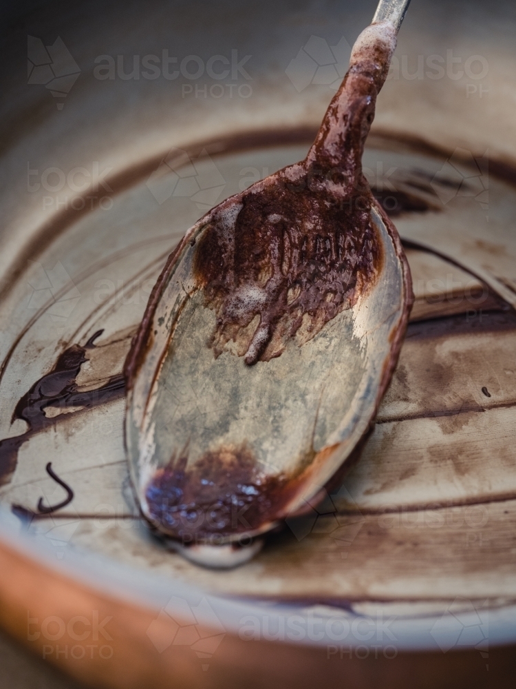 An empty bowl and spoon that has had chocolate icing  scraped out - Australian Stock Image