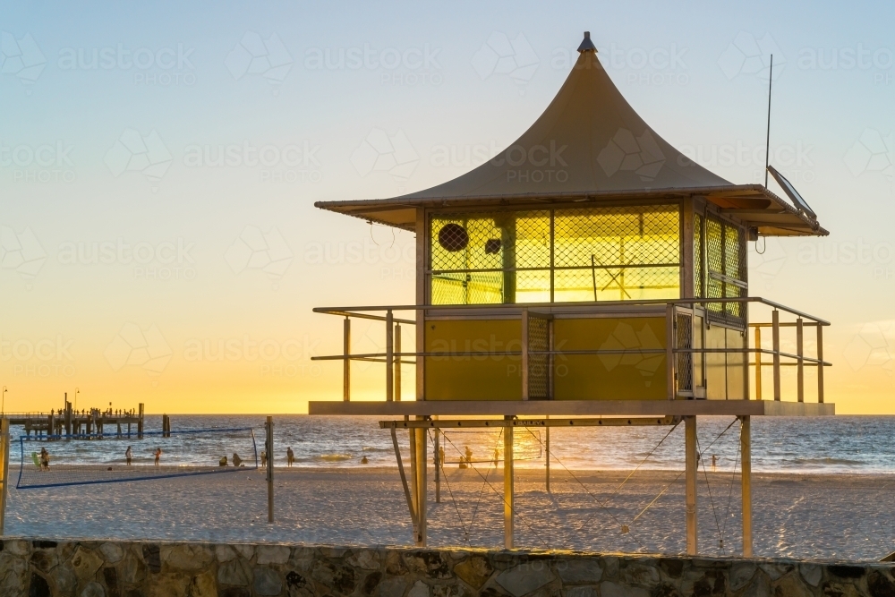 An empty surf lifesavers booth on Glenelg Beach backlit by the setting sun - Australian Stock Image
