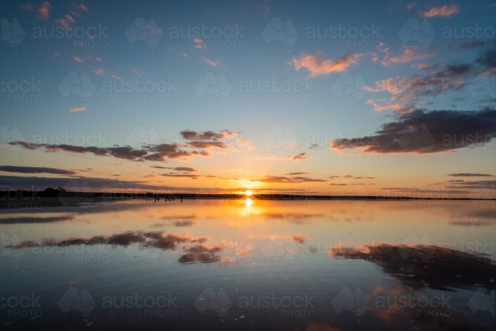 An expansive view of the sunset with reflections over a salt lake - Australian Stock Image