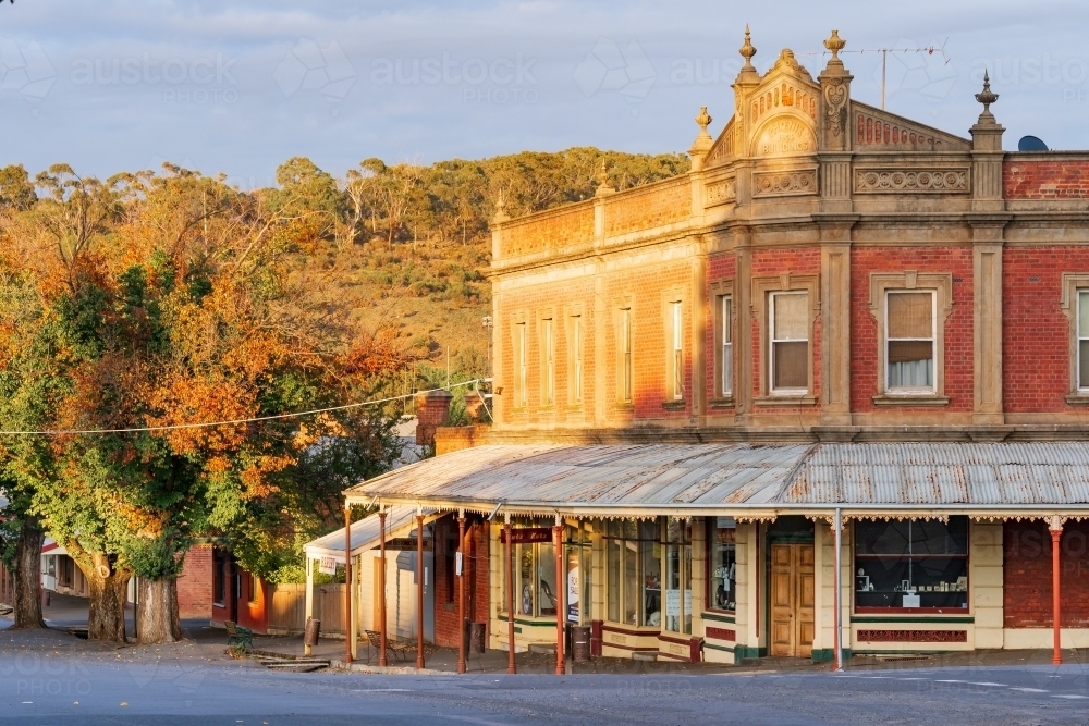 An historic corner building and autumn trees in morning sunshine - Australian Stock Image
