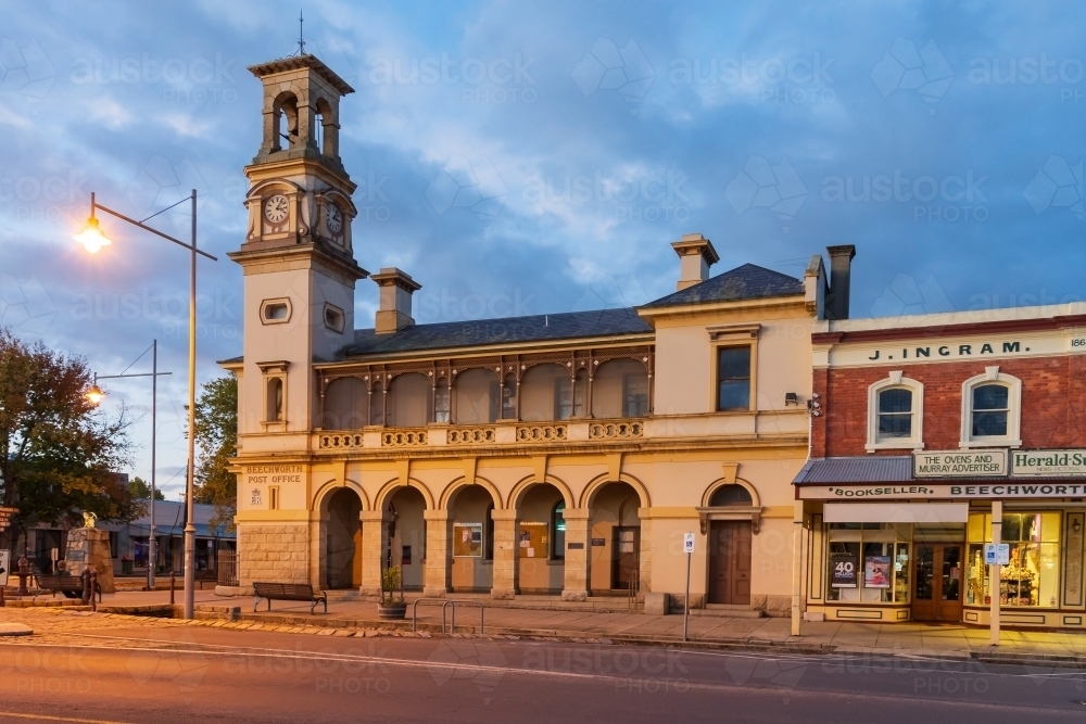 An historic Post Office building with a tall clock tower and arches on a street corner at twilight - Australian Stock Image