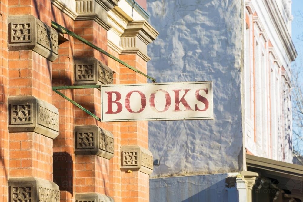 An old fashion "books" sign hangs from a historic brick building - Australian Stock Image