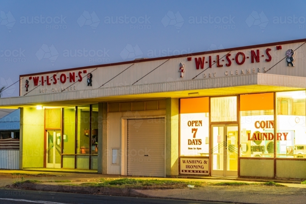 An old fashioned coin laundrette at twilight with bright lights coming from inside - Australian Stock Image
