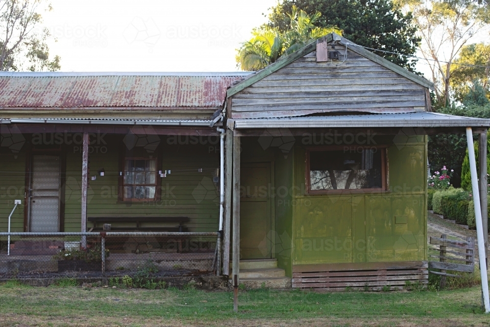 An old house with faded, peeling paint and rusty, corrugated roof - Australian Stock Image
