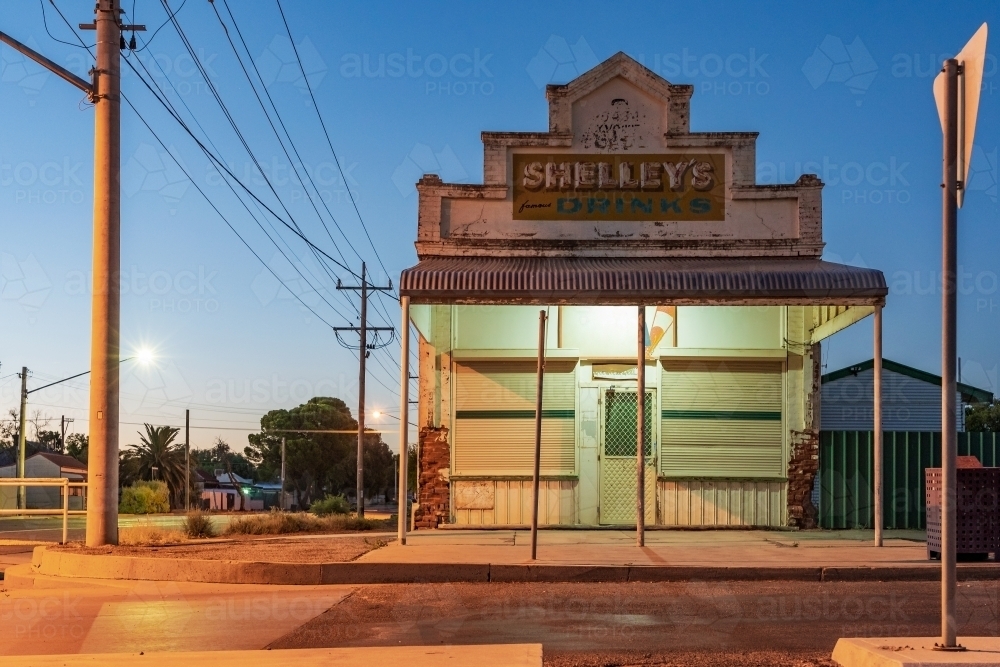Image of An old style corner milk bar at twilight under street lights