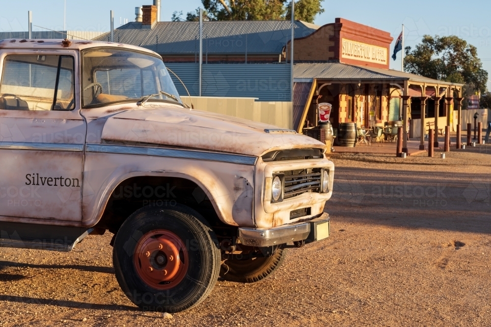 An old truck parked on the dirt surrounding an outback pub with a wide veranda - Australian Stock Image