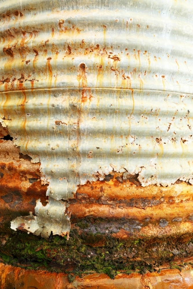 An old water tank rusting and leaking after a long life. - Australian Stock Image