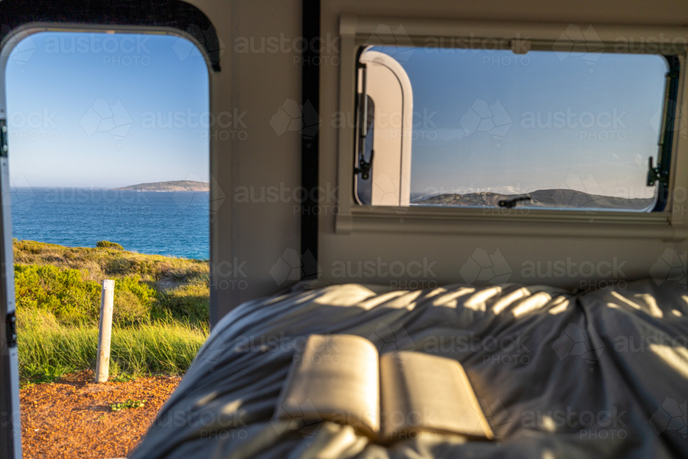 An open book on the bed inside camper van. - Australian Stock Image