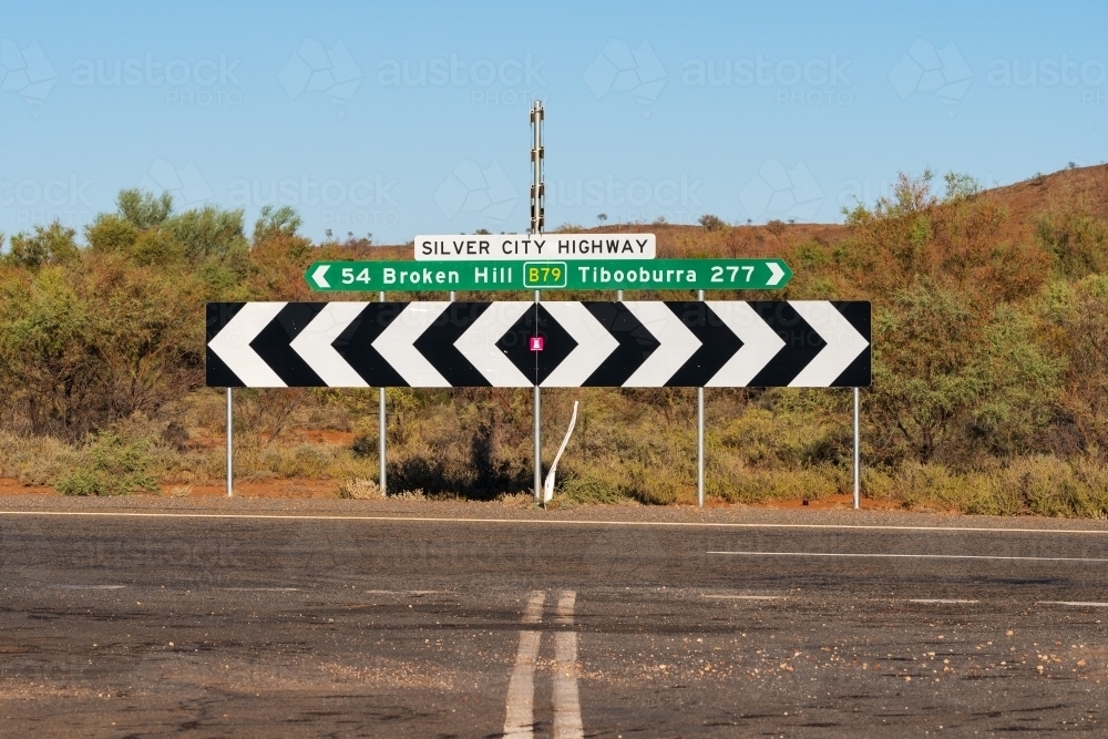 An outback T intersection with a graphic sign showing distances and directions - Australian Stock Image