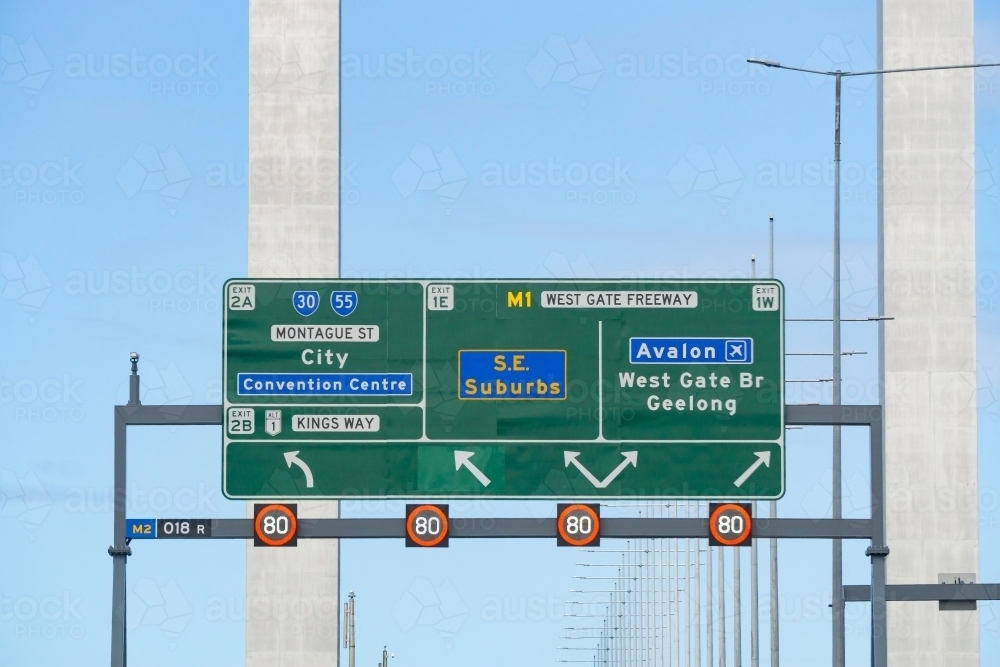 Image of An overhead traffic sign in front of bridge pylons - Austockphoto