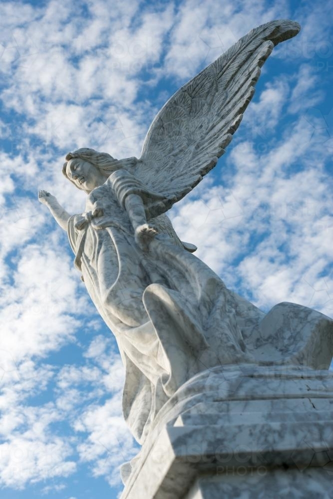 Angel on gravestone against clouded sky - Australian Stock Image