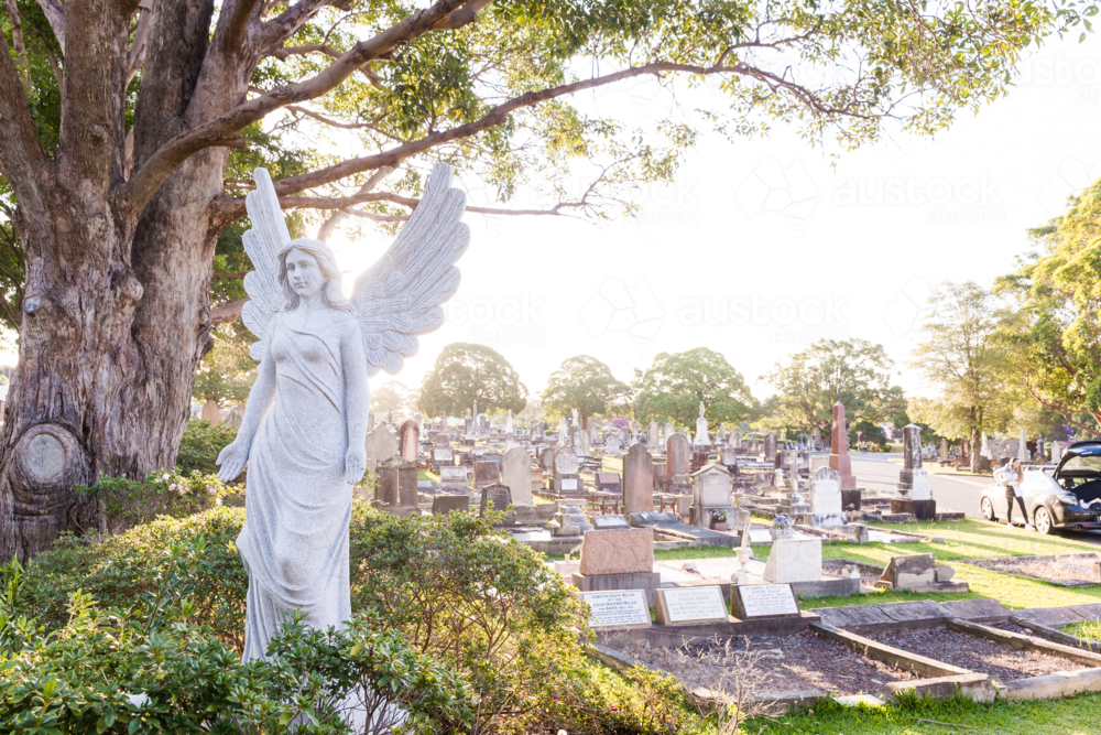 Angel sculpture and tombstones in a graveyard - Australian Stock Image