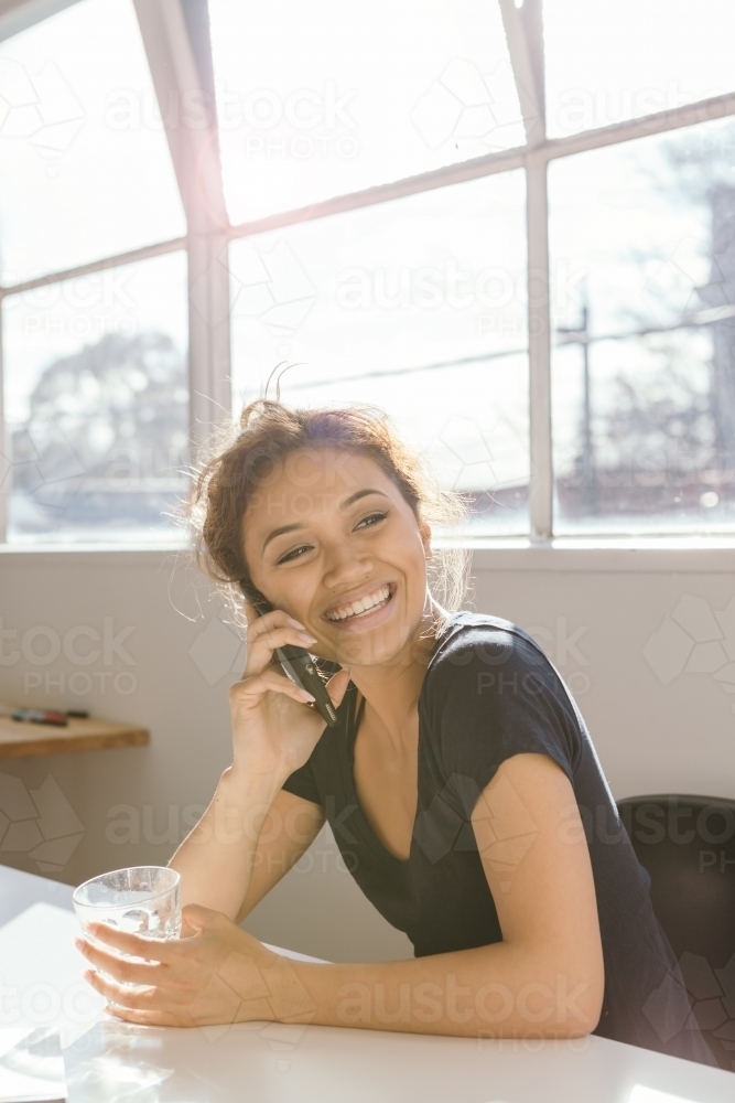 Animated young woman laughing while on the phone vertical - Australian Stock Image