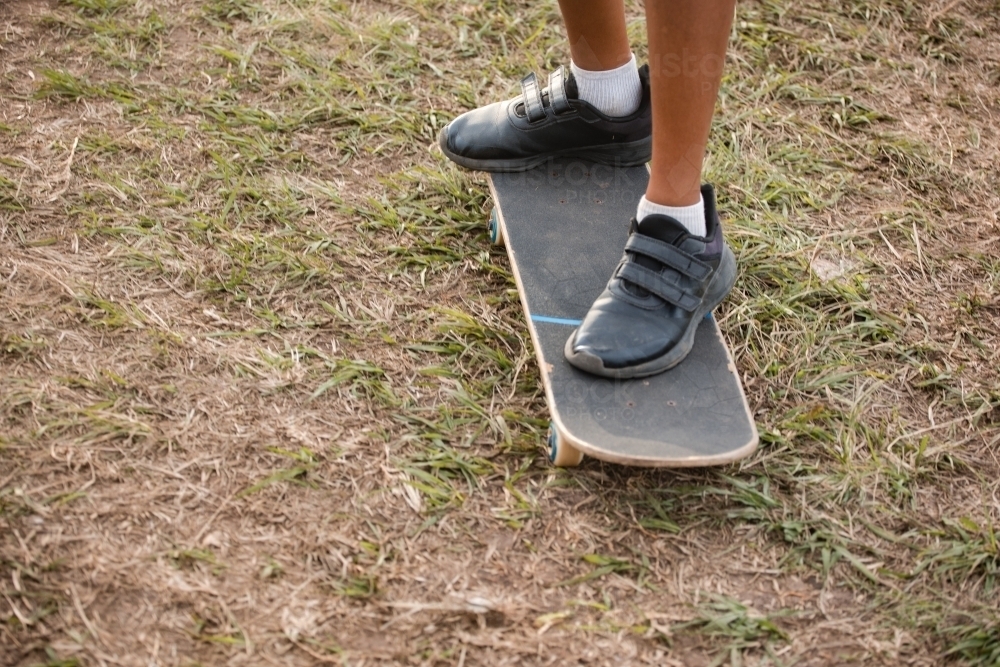 Ankle view of a child standing on a skateboard - Australian Stock Image