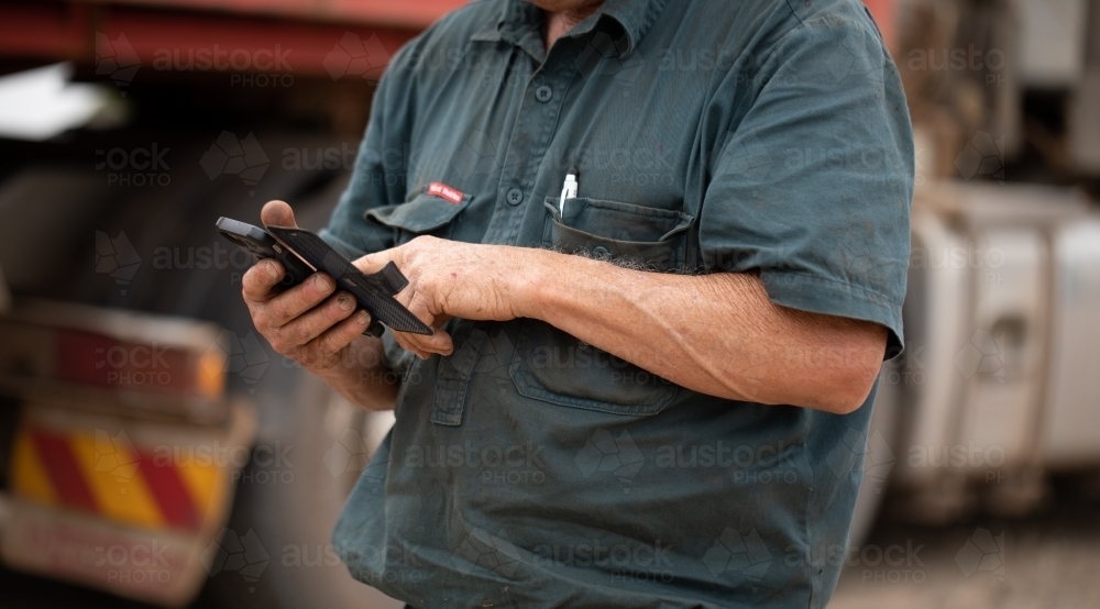 anonymous rural worker using smartphone - Australian Stock Image
