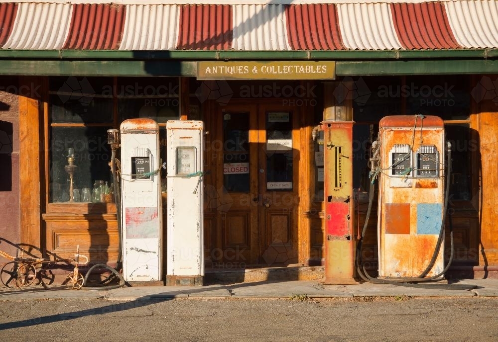 Antique petrol bowsers lined up in front of an Antique shop - Australian Stock Image
