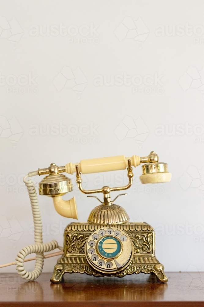 Antique telephone against blank wall - Australian Stock Image