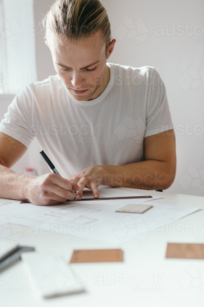 Architect using a ruler to draw a floor plan - Australian Stock Image