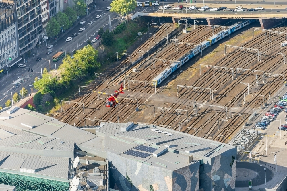 Arial view of a helicopter flying over a commuter train in a railway yard - Australian Stock Image