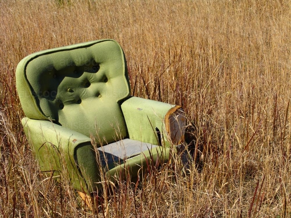 Armchair sitting in a paddock of dry grass - Australian Stock Image