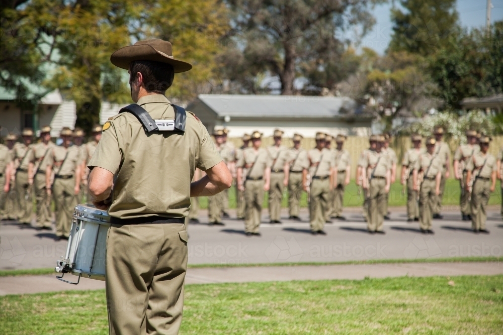 Army drummer playing in front of soldiers standing to attention - Australian Stock Image