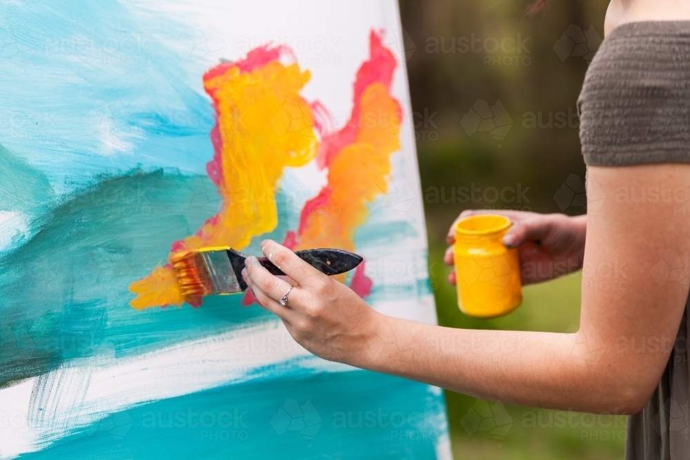 Artist with brush beginning an acrylic painting on canvase - Australian Stock Image