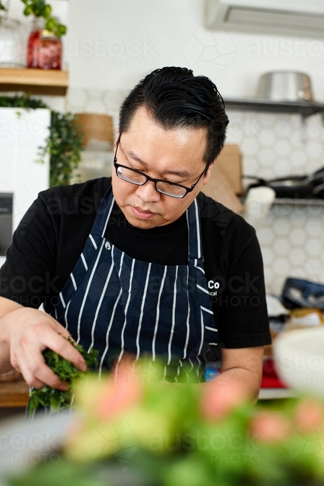 Asian chef working in kitchen at organic food cafe - Australian Stock Image
