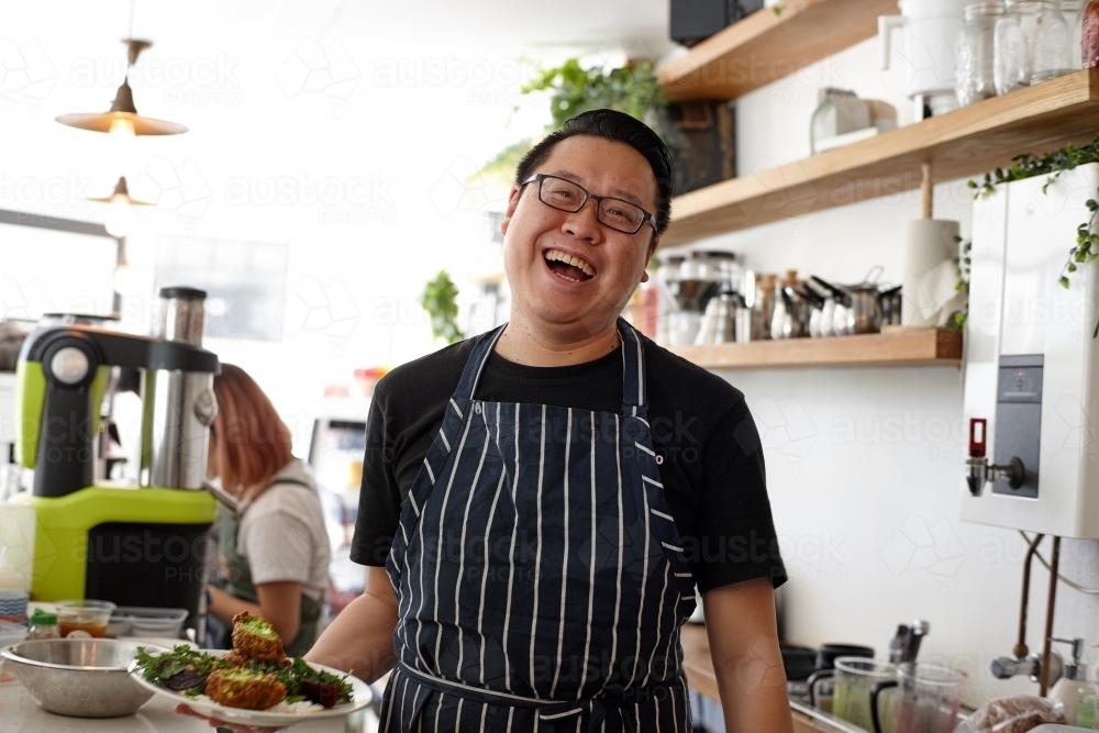 Asian chef working in kitchen at organic food cafe - Australian Stock Image