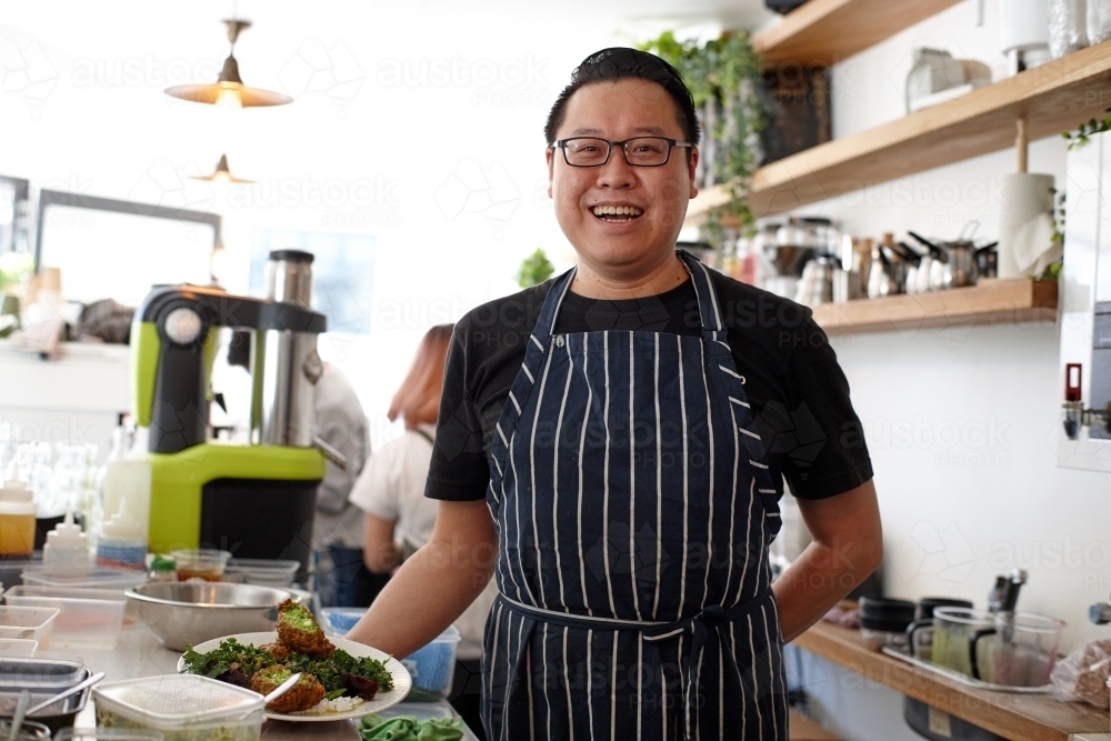 Asian chef working in kitchen at organic food cafe - Australian Stock Image