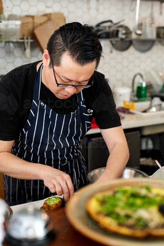 Asian chef working in kitchen at organic food cafe - Australian Stock Image