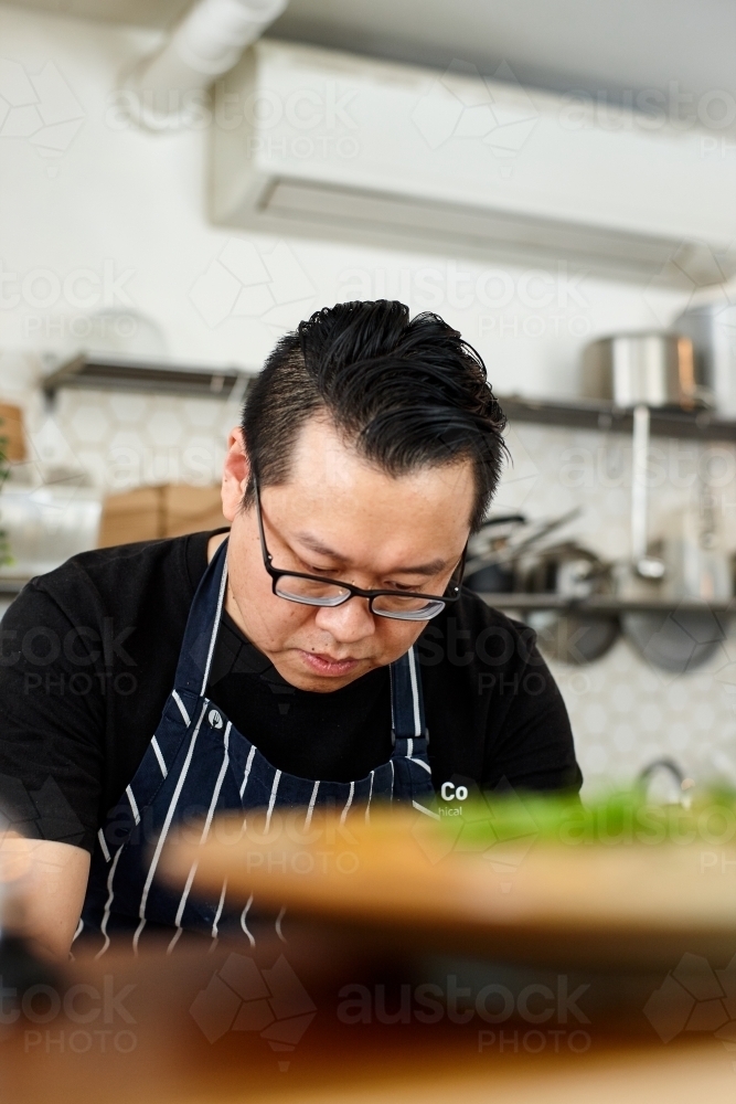 Asian chef working in kitchen at organic food cafe - Australian Stock Image