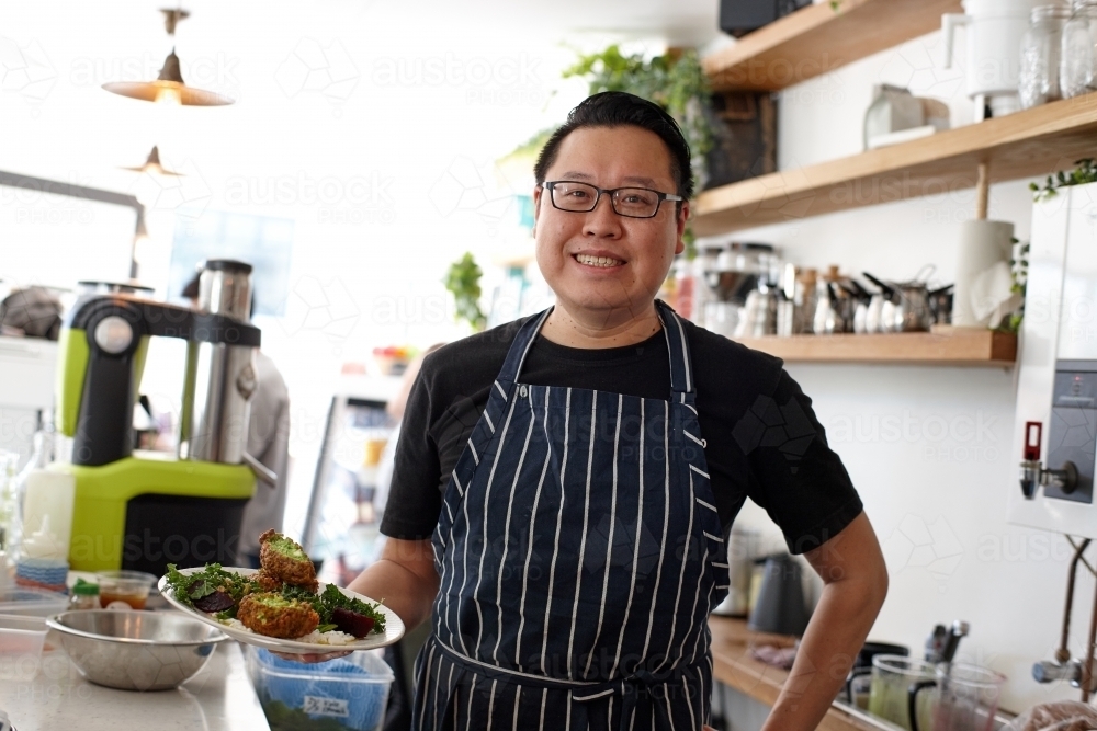 Asian chef working in kitchen at organic food cafe - Australian Stock Image