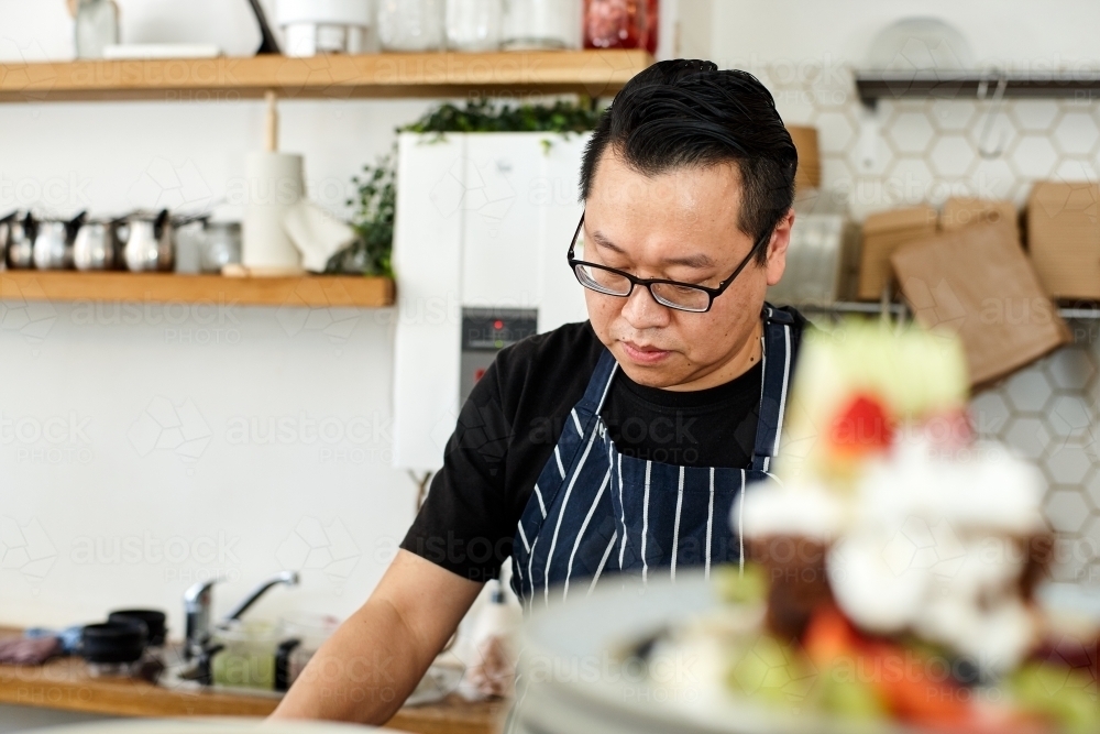 Asian chef working in kitchen at organic food cafe - Australian Stock Image