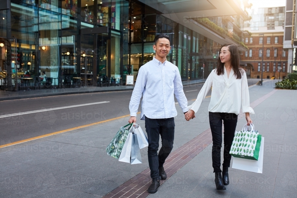 Asian couple enjoying shopping in city together - Australian Stock Image